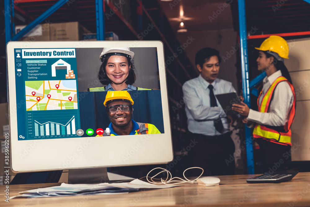 Warehouse staff talking on video call at computer screen in storage warehouse . Online software tech