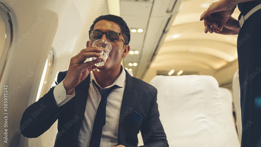 Cabin crew serve water to passenger in airplane . Airline transportation and tourism concept.