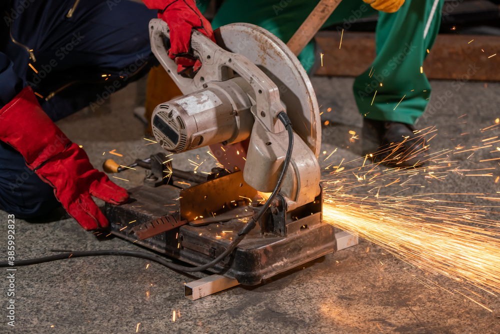 Professional mechanic man is cutting steel metal with rotating carbon blade cutter. Steel industry a