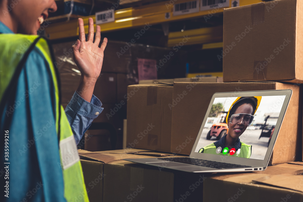 Warehouse staff talking on video call at computer screen in storage warehouse . Online software tech