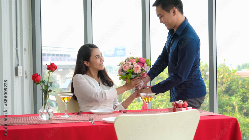 Romantic couple giving gift to lover at restaurant . Happy couple lifestyle .