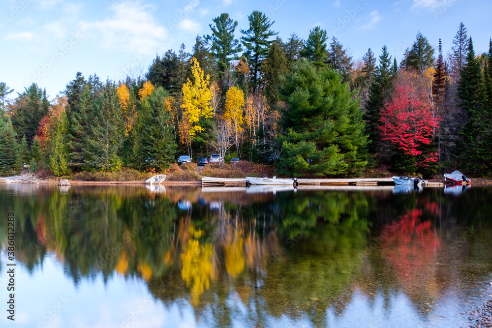 Beautiful Canadian landscape: Green, yellow and red tree reflecting in a lake