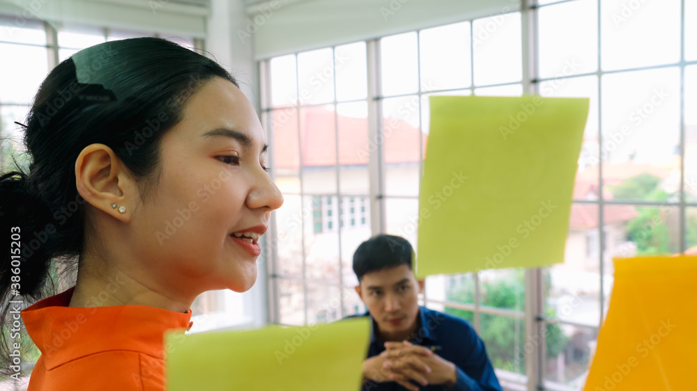 Business people work on project planning board in office and having conversation with coworker frien