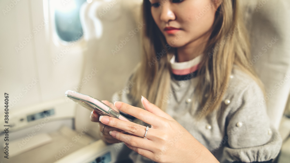 Asian woman using mobile phone in airplane . Travel and internet connection concept .