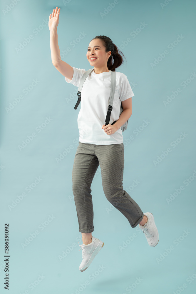 Full length photo of cheerful girl hold backpack jump run go lesson greet teacher classmates over bl