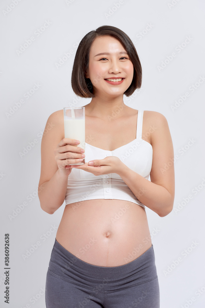 Pregnant woman drinking milk on the white background.