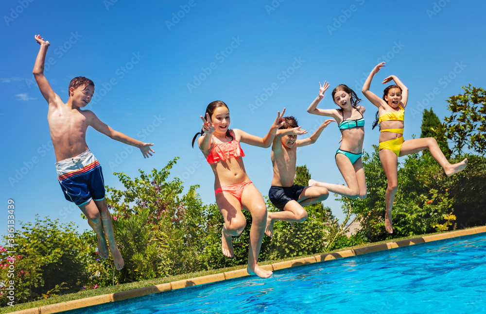 Many friends, kids jump with lifted hands in water pool outside during summer vacation