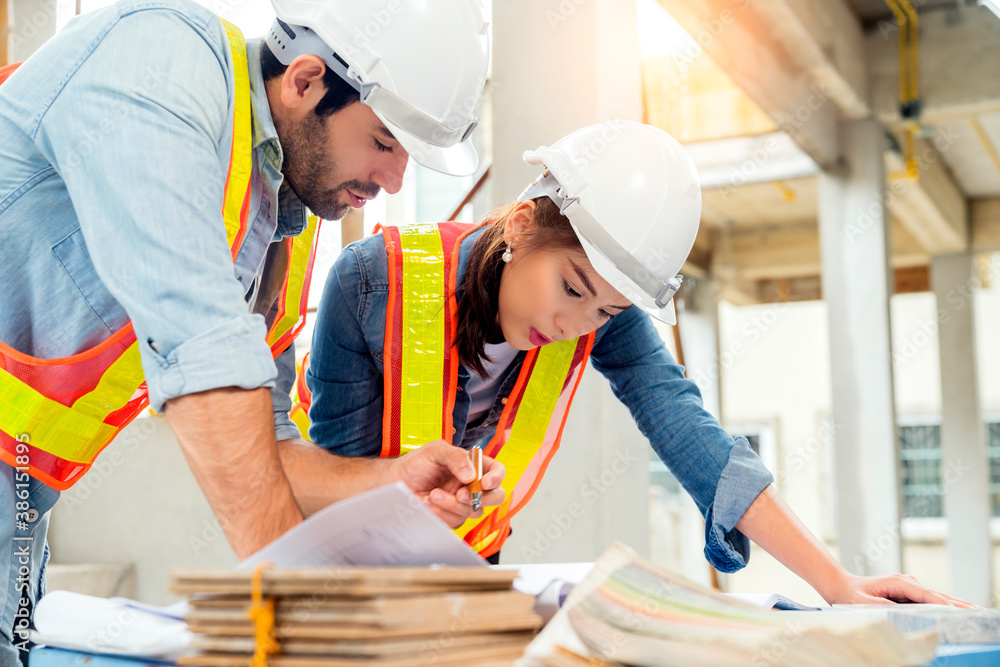 Young Asian engineers and caucasian engineer colleagues at site inspector and discuss together using