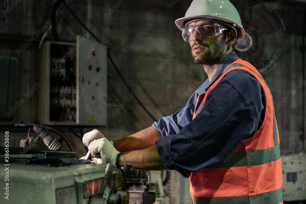 A male engineer is working in an industrial factory. And wear a helmet for safety while working. Con