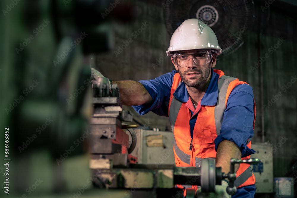 A male engineer is working in an industrial factory. And wear a helmet for safety while working. Con