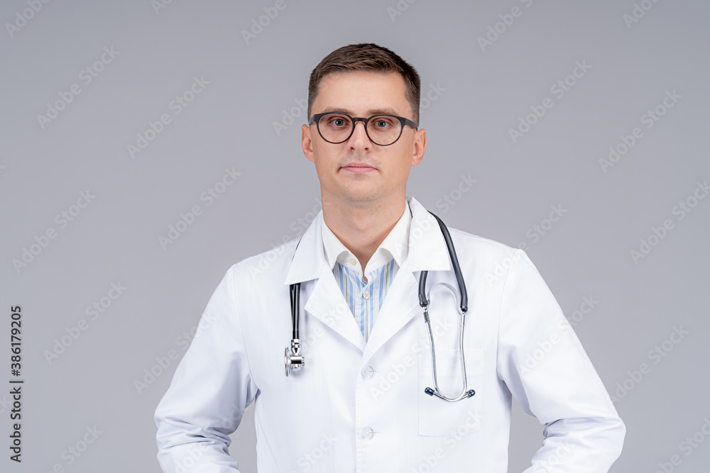 Portrait of a doctor or medical specialist. Horizontal half length portrait. Man in scrubs. Light gr