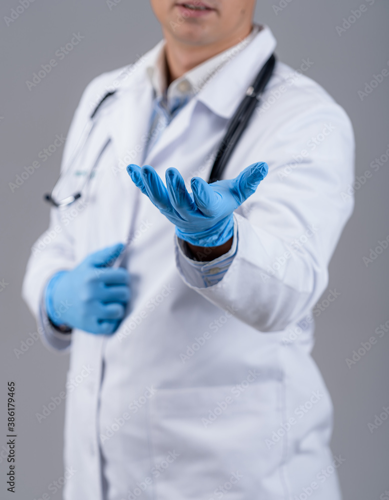 Doctor is showing one hand in blue medical gloves to the camera. Medic in white scrubs with phonendo