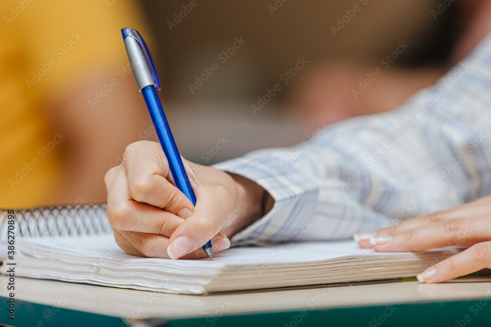 Latin students in the classroom. female student holding a pen and writing in notebook