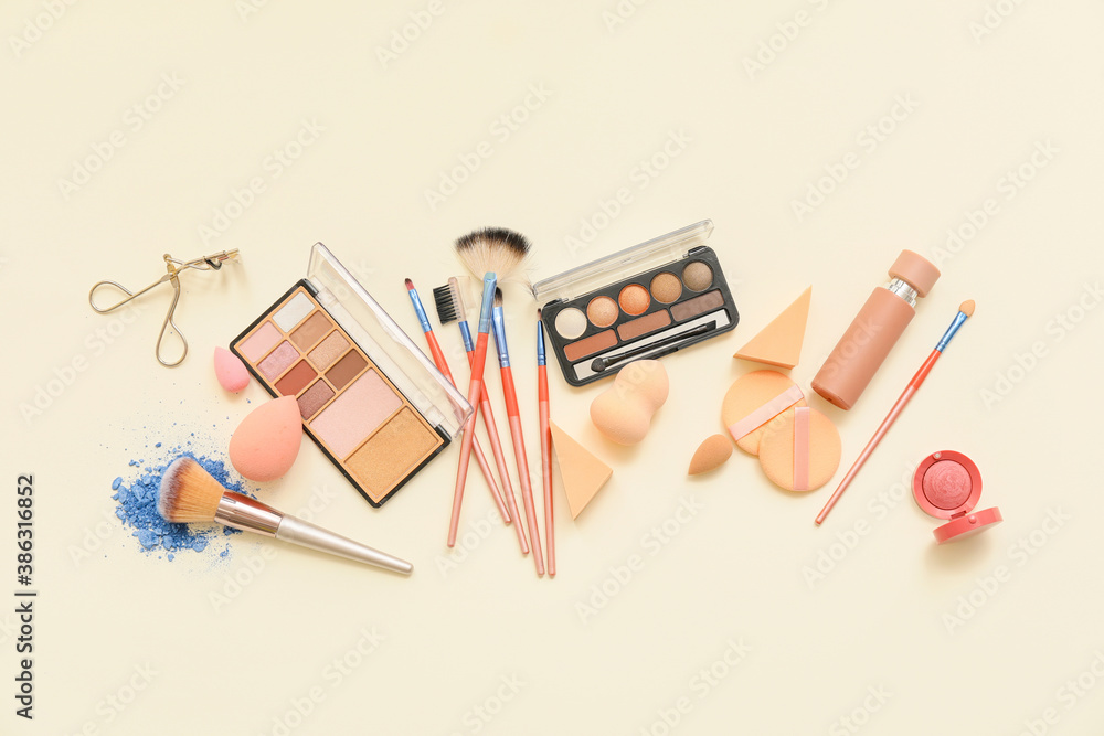 Set of makeup brushes with decorative cosmetics on light background