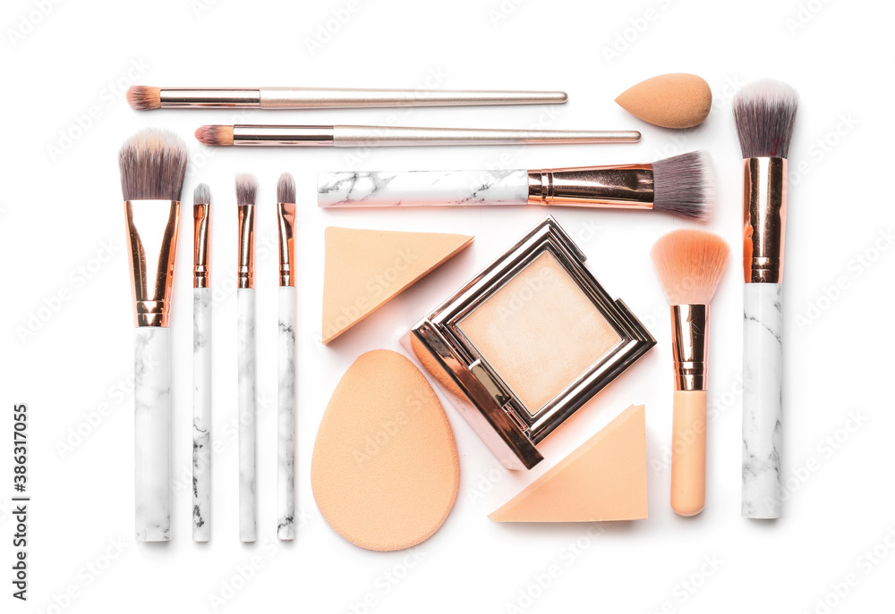 Set of makeup brushes with decorative cosmetics and sponges on white background