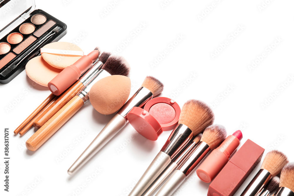 Set of makeup brushes with decorative cosmetics and sponges on white background