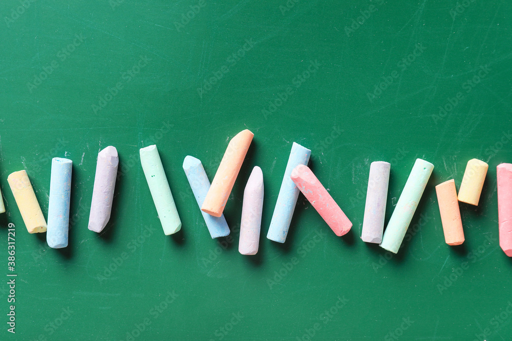 Pieces of colorful chalk on blackboard, top view