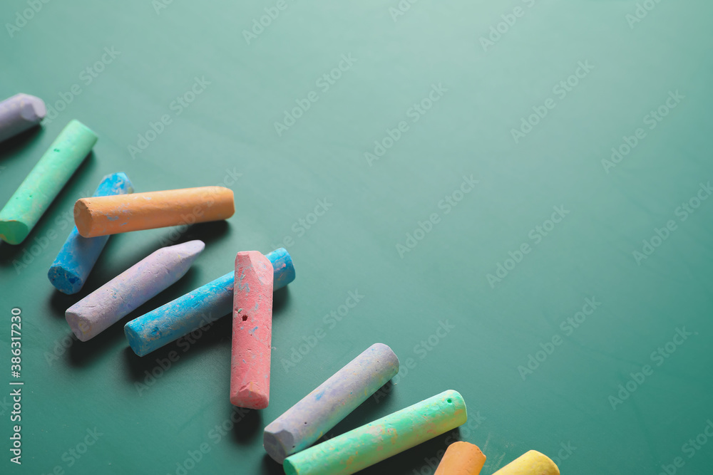 Pieces of colorful chalk on blackboard