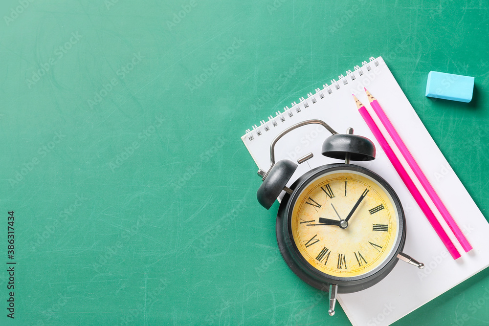 Set of school stationery with alarm clock on blackboard