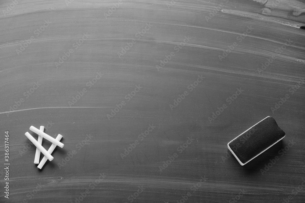 Sponge and pieces of chalk on blackboard, top view