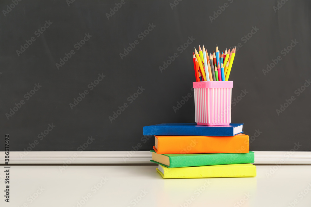 Holder with pencils and books on table in classroom