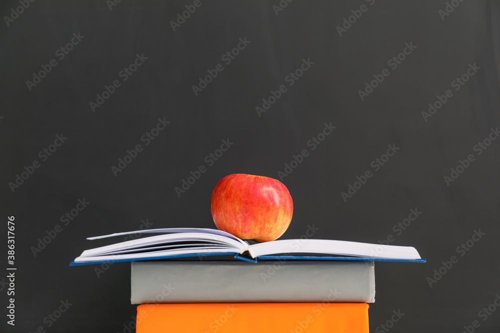 Books with apple near chalkboard in classroom