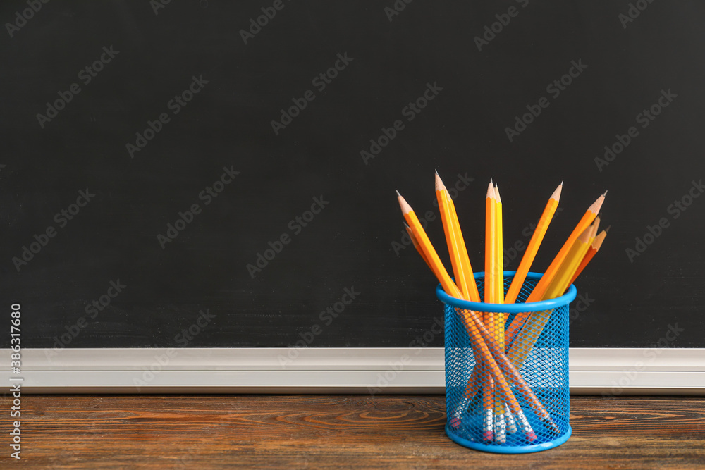 Holder with pencils on table in classroom