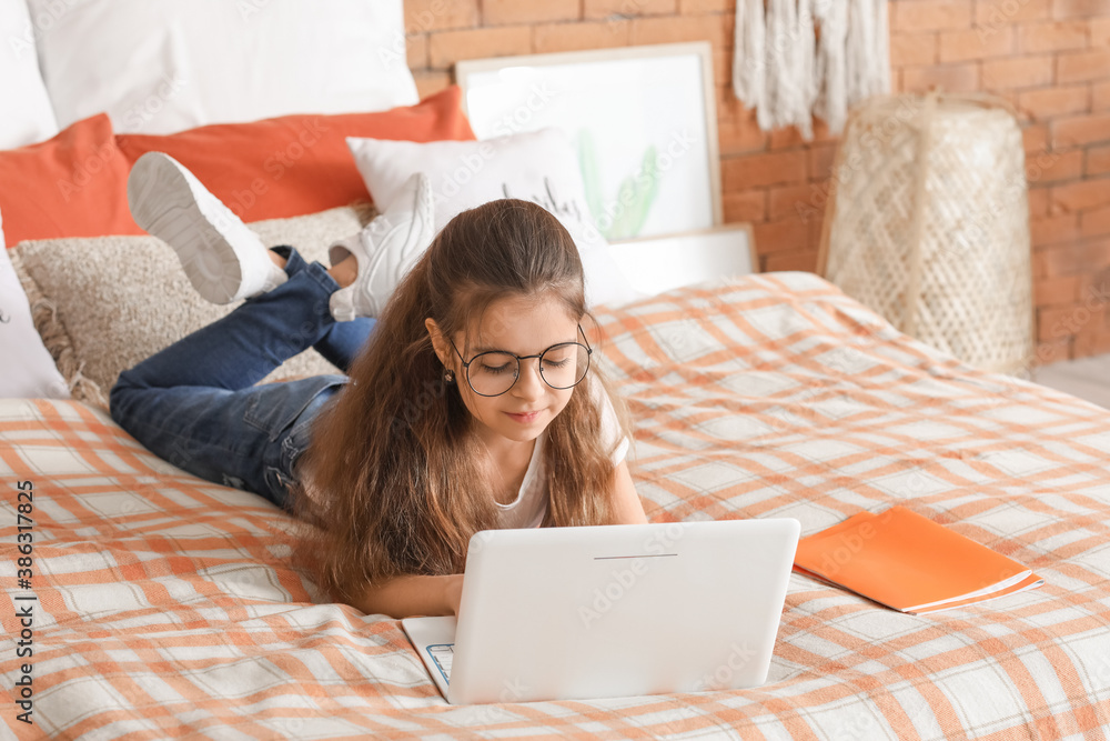 Cute little girl with laptop in bedroom