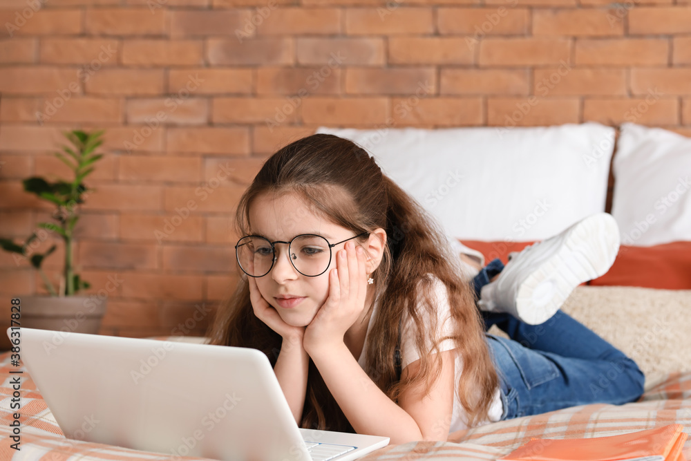 Cute little girl with laptop in bedroom