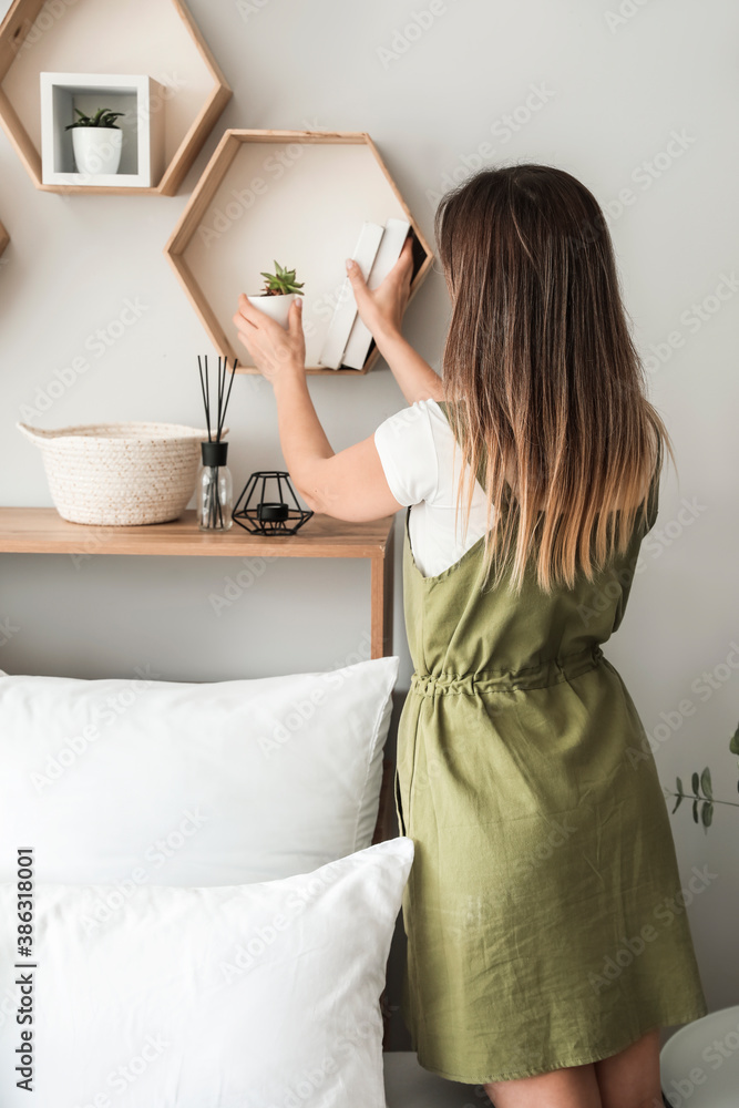 Young woman near wooden shelves in bedroom