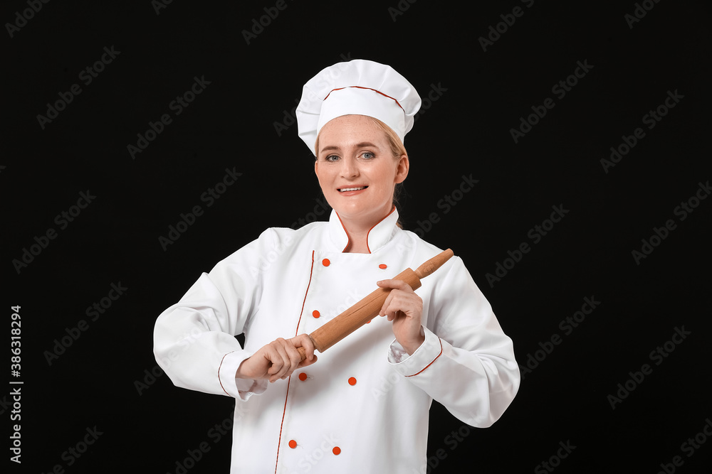 Mature female chef with rolling pin on dark background