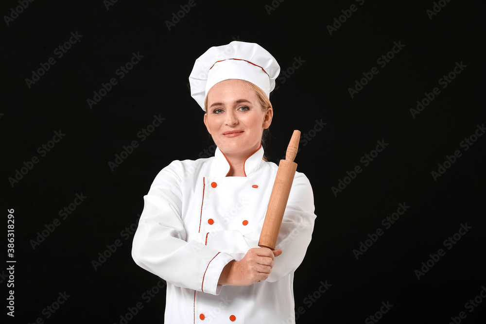 Mature female chef with rolling pin on dark background