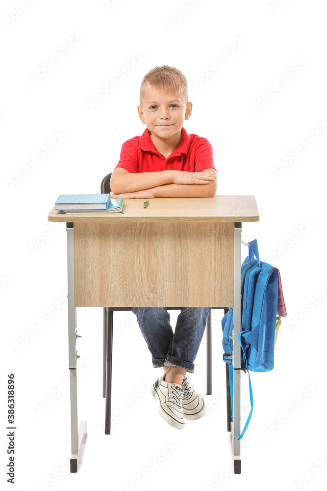 Little pupil sitting at school desk against white background