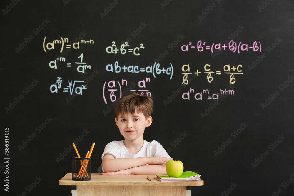 Cute pupil sitting at desk during lesson in classroom