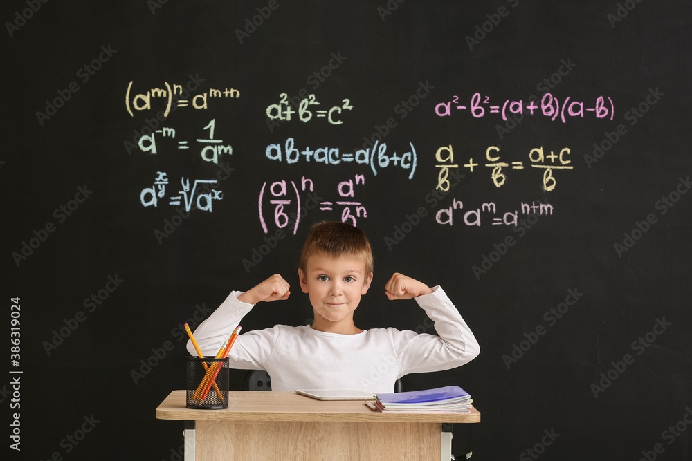 Cute pupil sitting at desk during lesson in classroom