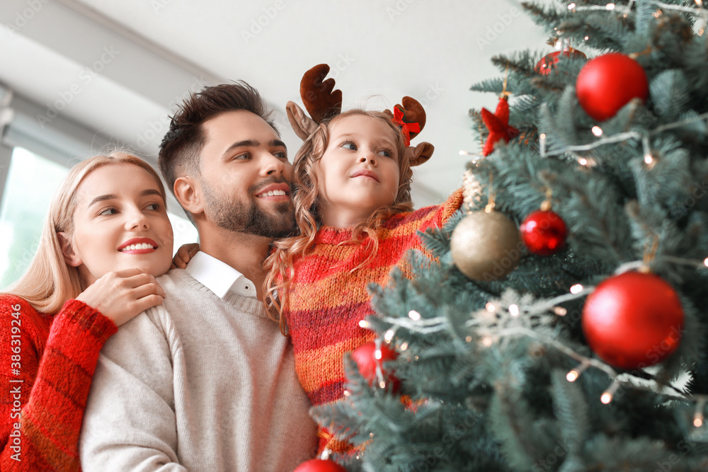 Young family decorating Christmas tree at home