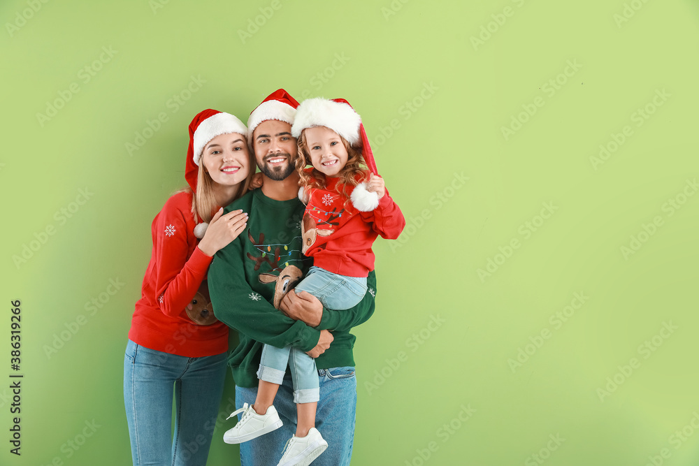 Young family in Santa Claus hats on color background. Christmas celebration