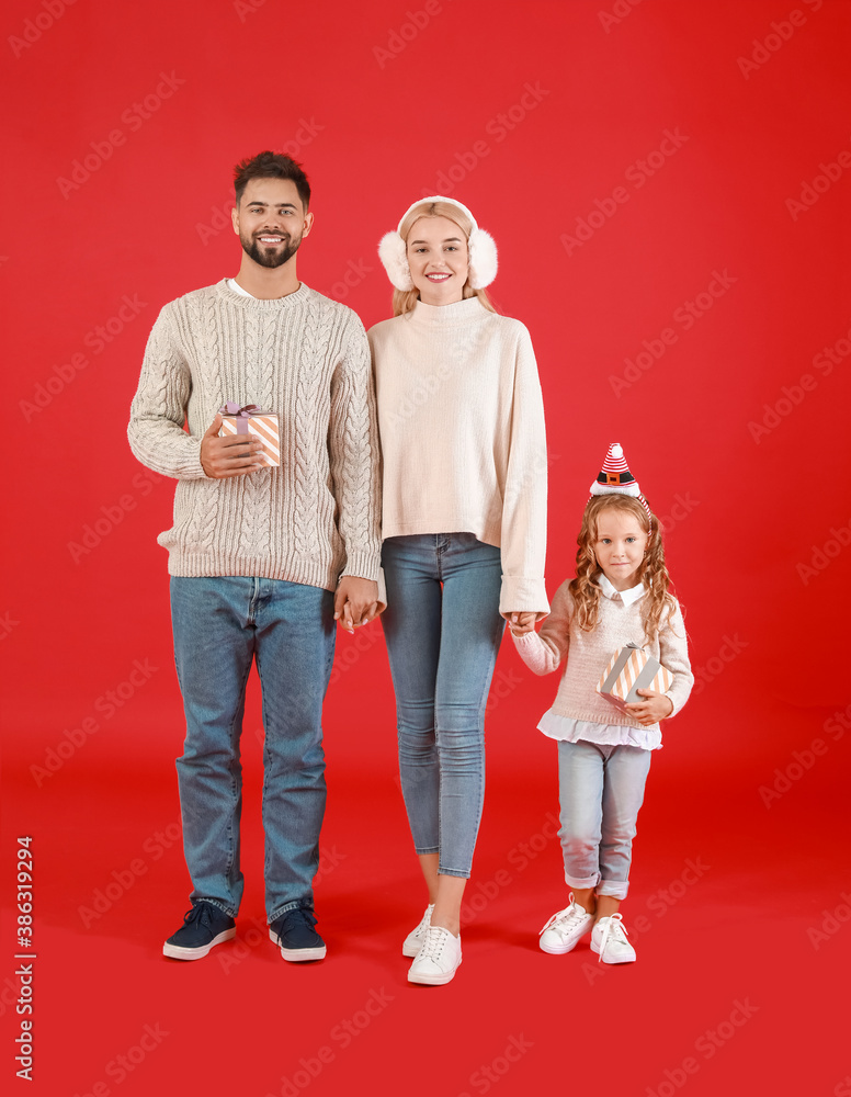 Young family with Christmas gifts on color background