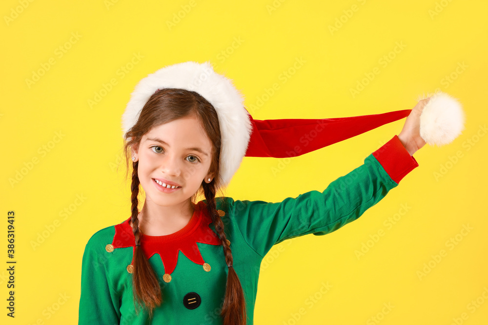 Cute little girl dressed as elf on color background