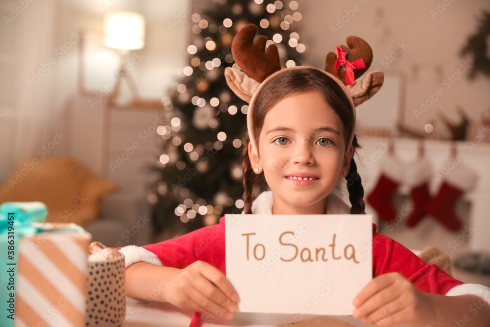 Cute little girl with letter to Santa at home on Christmas eve