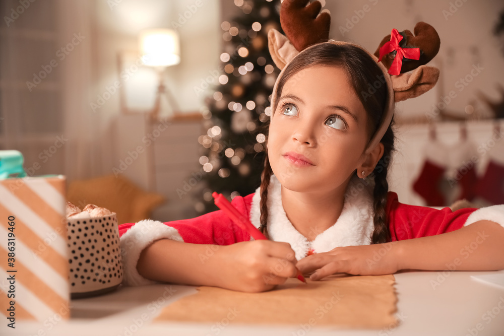 Cute little girl writing letter to Santa at home on Christmas eve