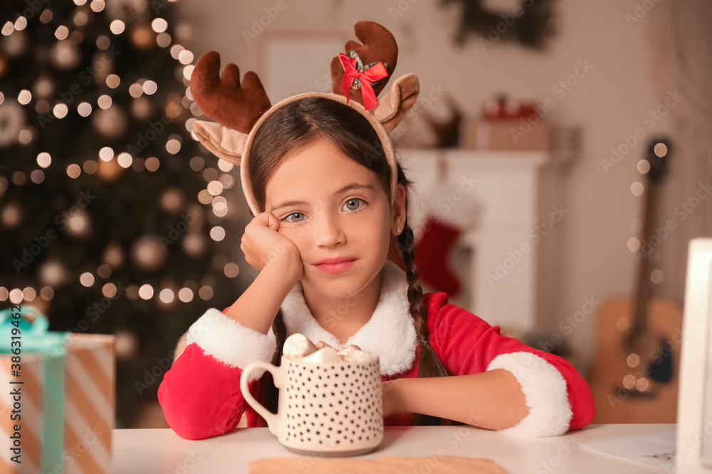 Cute little girl with cup of hot chocolate at home on Christmas eve