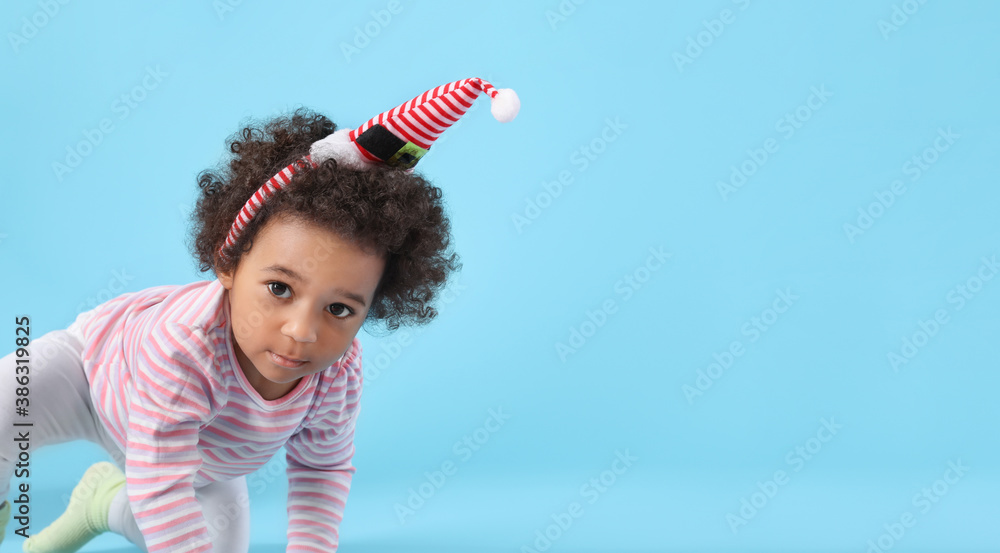 Cute African-American baby girl on color background. Christmas celebration