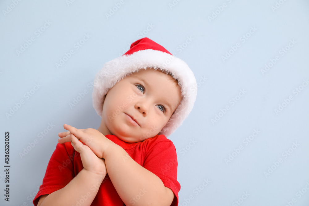 Cute little baby in Santa hat on color background