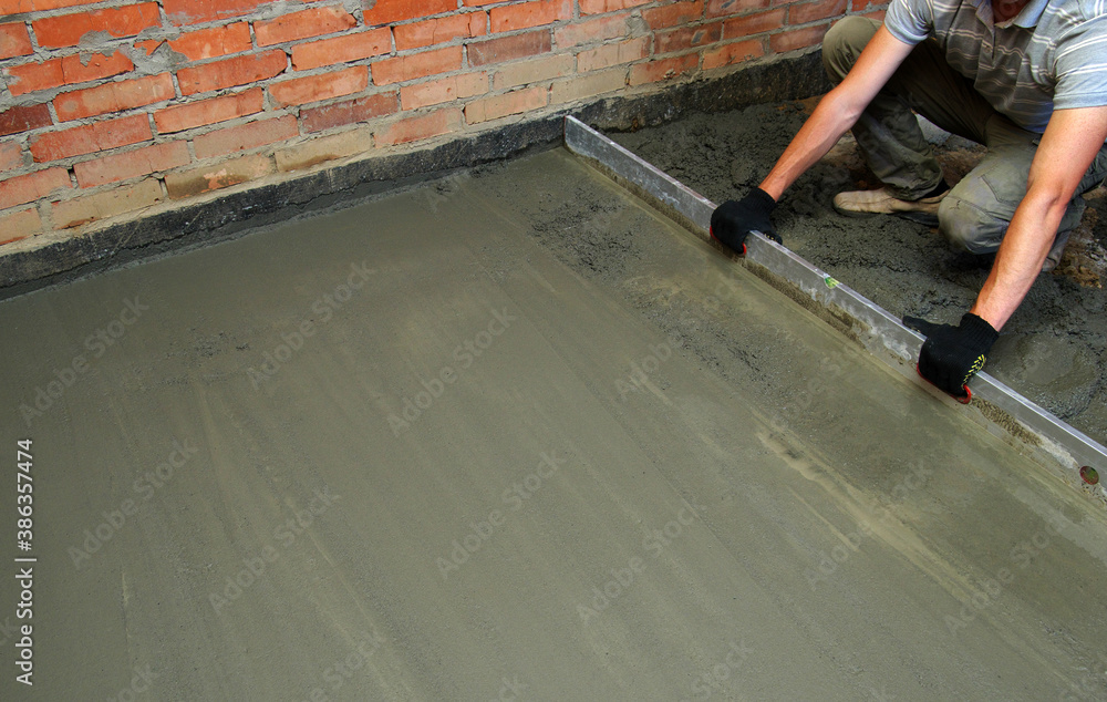 worker screeding indoor cement floor with screed