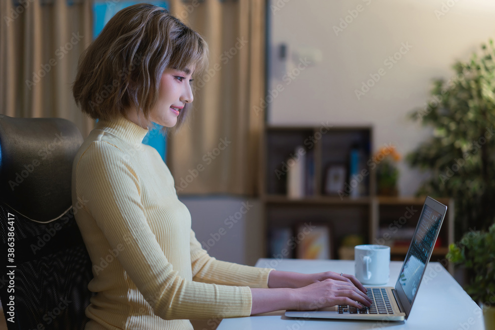 Asian woman Use the computer to work at night at her house.