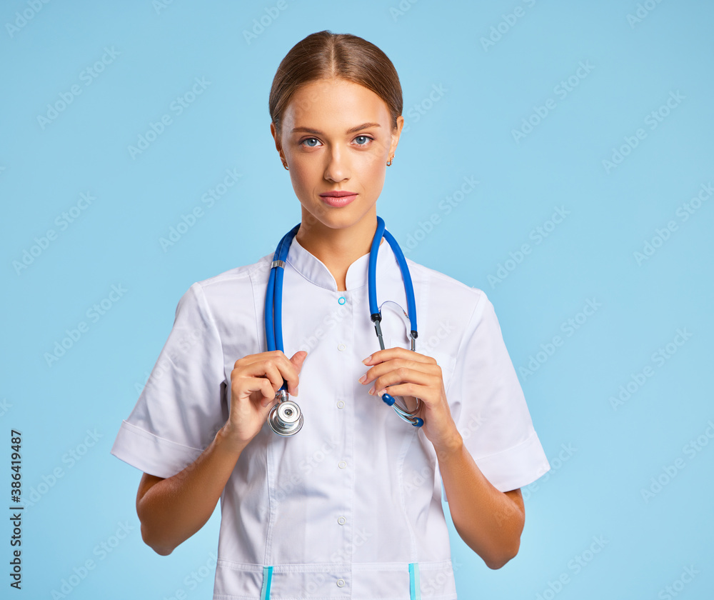 friendly doctor nurse in a   uniform smiles in isolation against a blue background.