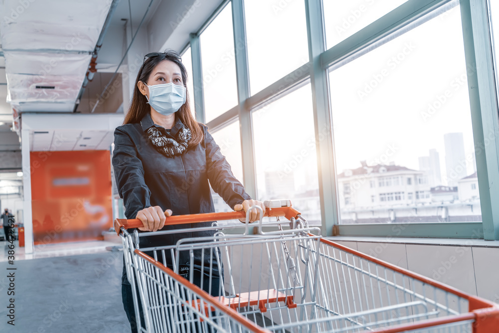 Woman shopping with hand pushing cart in supermarket parking lot