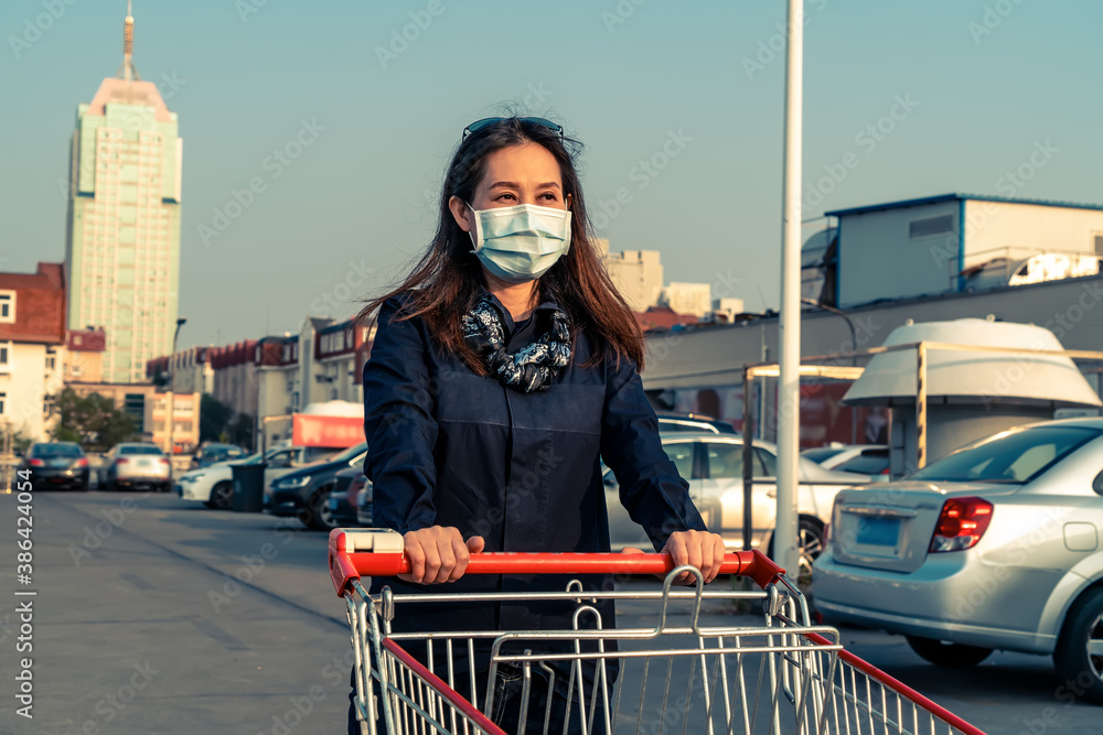 Woman shopping with hand pushing cart in supermarket parking lot