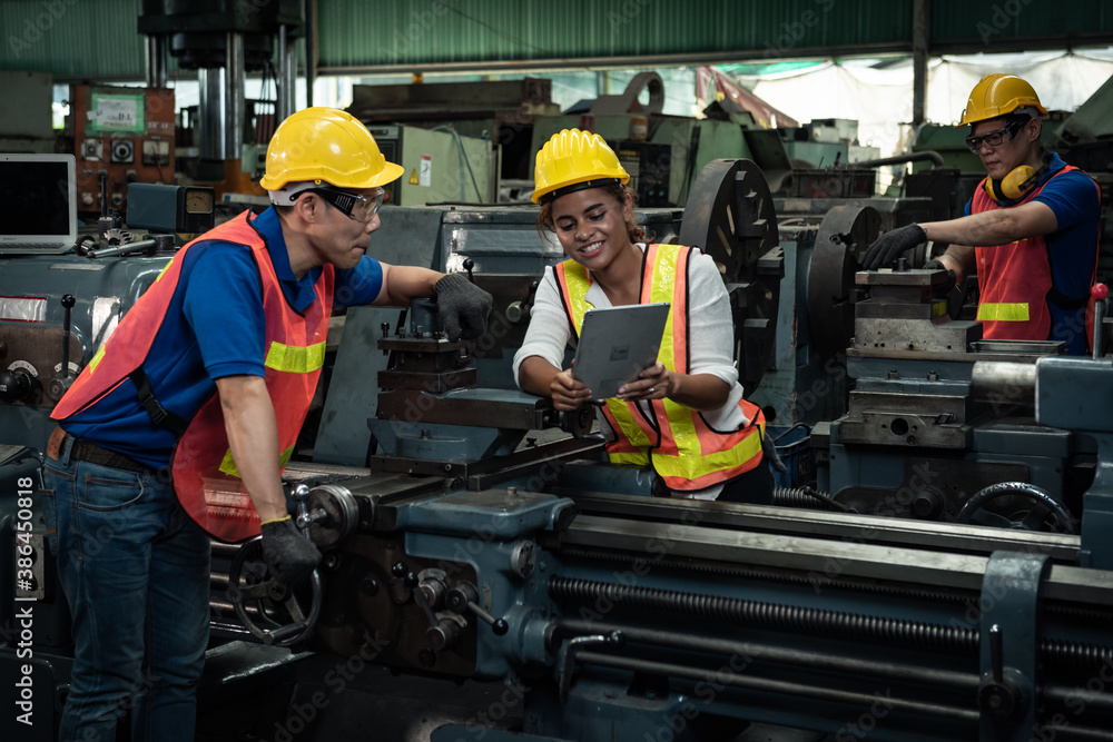 Male and female engineers are working on industrial machines. And wear a helmet for safety while wor